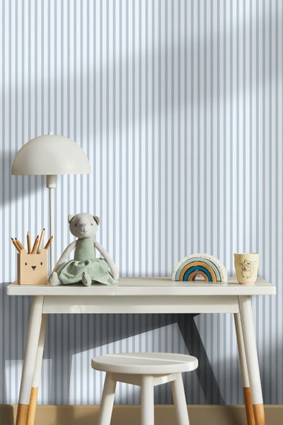 Kinderzimmer mit Schreibtisch, Lampe, Hocker und gestreifter Tapete