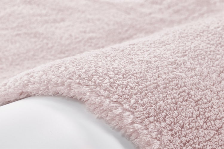 Nahaufnahme eines weichen Hochflor-Teppichs in Rosa, der die flauschige Textur und die dichten Fasern zeigt.