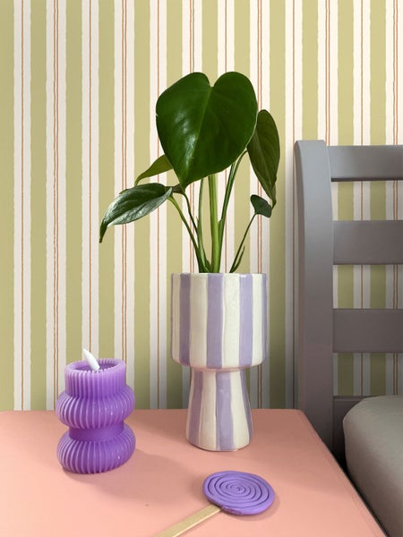 Dekorative Szene mit Zimmerpflanze, gestreifter Vase und Kerze auf einem Nachttisch