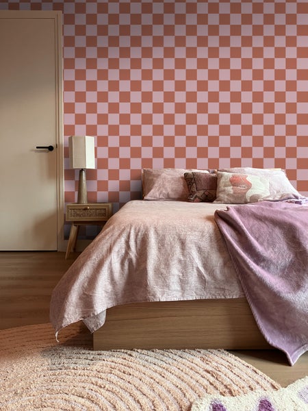 Schlafzimmer mit Bett, Nachttisch, Lampe und karierter Tapete