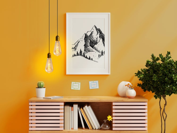 Dekoratives Zimmer mit Kommode, Lampe und gerahmtem Bergmotiv