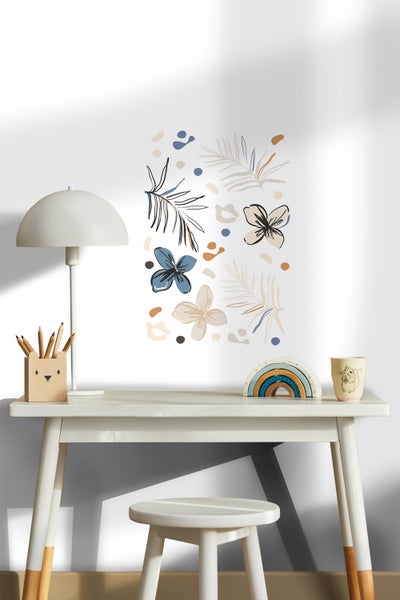 Kinderzimmer mit Schreibtisch, Lampe, Stiftköcher, Regenbogen Spielzeug, Tasse und Wandtattoo mit Blumen- und Blättermotiven.