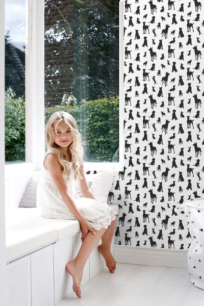 Mädchen sitzt in einem Zimmer mit Hundetapete