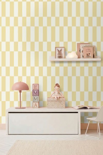 Modernes Kinderzimmer mit gelb und weiß gemusterter Tapete, einem weißen Sideboard, einem Wandregal mit Büchern und einem Schreibtischbereich.