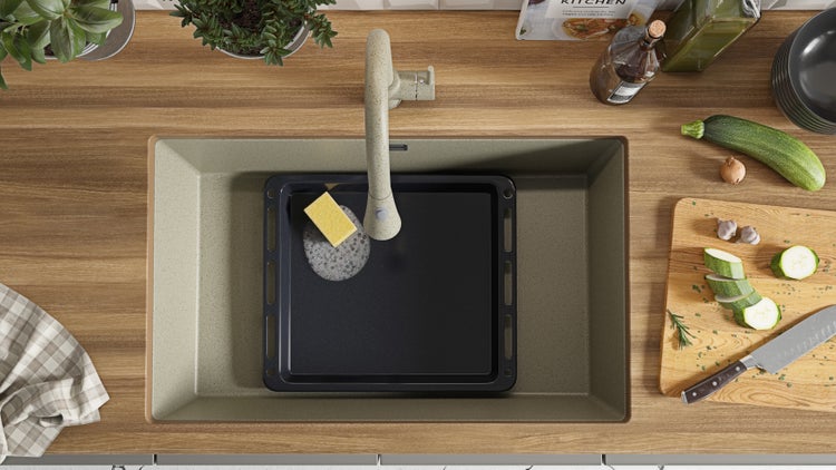 Küchenspüle mit Abtropffläche, Spülmittel und Gemüse auf einer Holzarbeitsplatte
