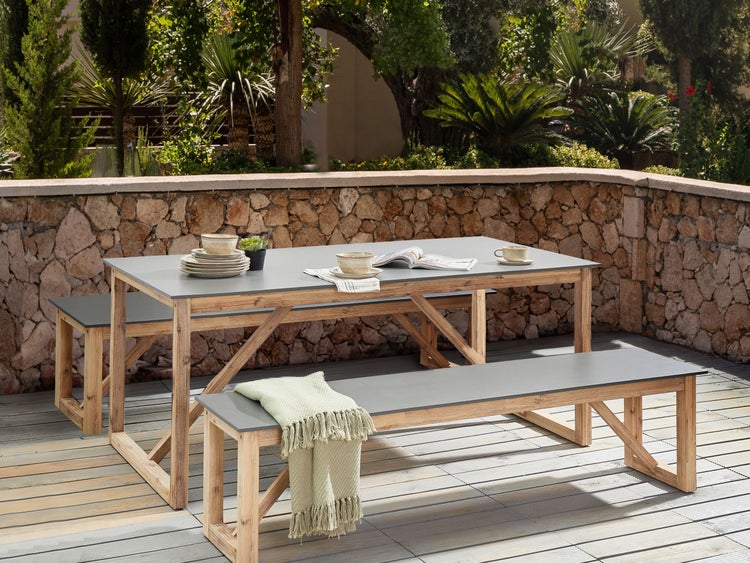 Gartensitzgruppe mit Tisch und zwei Bänken auf einer Terrasse.