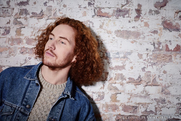 Dekorative Szene mit Laterne, Kissen, Korb und Holzelementen vor einer Mauer in Steinoptik