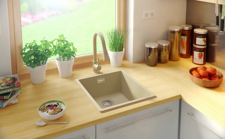 Küchenspüle aus Granit mit Armatur und Lebensmitteln auf der Küchentheke