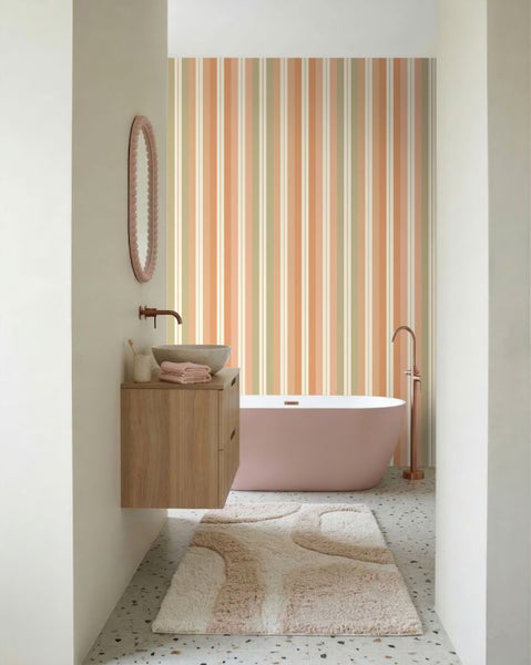 Modernes Badezimmer mit gestreifter Tapete in Orange und Grün, freistehender Badewanne und Waschtisch aus Holz.