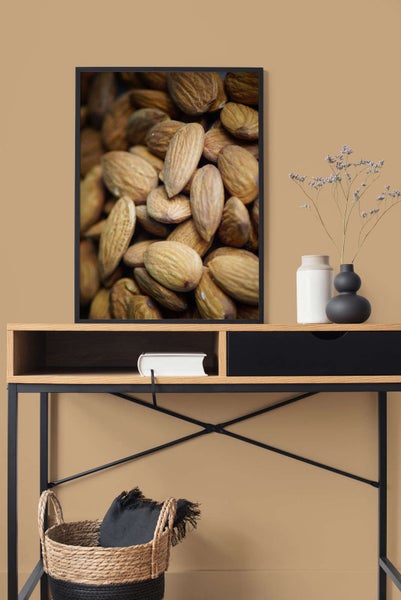 Gerahmtes Wandbild mit einer Nahaufnahme von Mandeln, aufgehängt über einem modernen Konsolentisch aus Holz und Metall.
