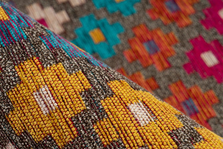 Nahaufnahme eines gewebten Teppichs mit geometrischem Kilim-Muster und grober Textilstruktur.