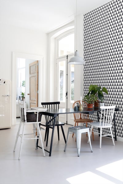 Heller Raum mit Esstisch, Stühlen und geometrischer Tapete