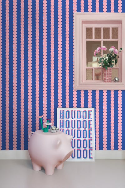 Raumansicht mit blau-rosa Tapete, Fenster, rosa Sparschwein und Poster