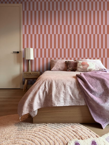 Schlafzimmer mit Bett, Nachttisch und gestreifter Tapete