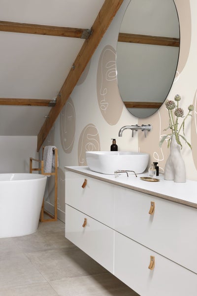 Badezimmer mit Waschbecken, Spiegel und weißen Möbeln unter einer Dachschräge mit Holzbalken