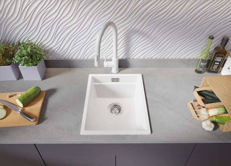 Küchenszene mit Spüle, Armatur und Lebensmitteln auf einer Arbeitsplatte.