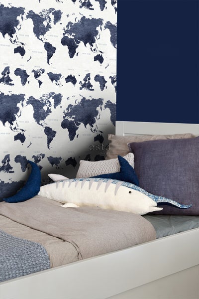 Dekoratives Schlafzimmer mit Weltkarten-Tapete und Zierkissen