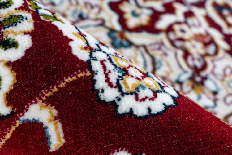 Nahaufnahme eines Teppichs mit orientalischem Muster in Rot und Weiß sowie weichem Flor.