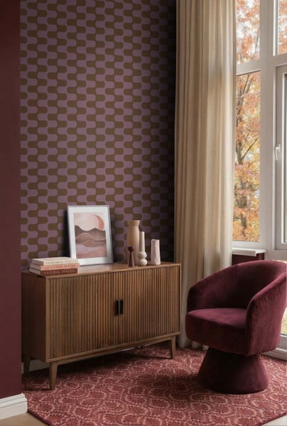 Wohnzimmer mit geometrisch gemusterter Tapete, hölzernem Sideboard mit Lamellenfront, Samtsessel und gemustertem Teppich.