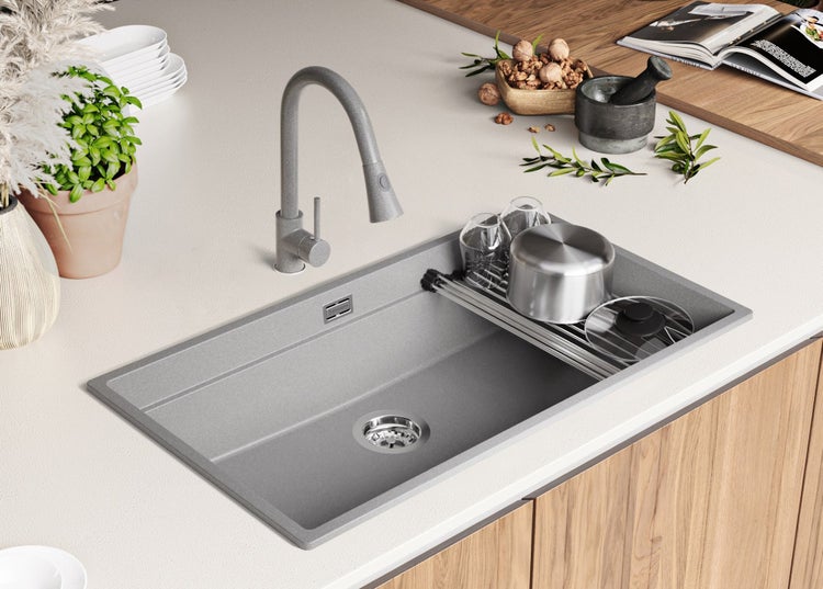 Küchenspüle mit Armatur, Abtropfgestell und Geschirr auf einer Küchentheke.