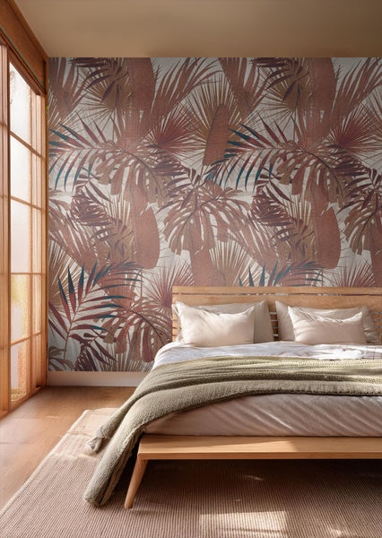 Schlafzimmer mit tropischer Blättertapete hinter einem Holzbett
