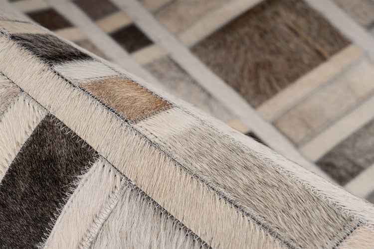 Nahaufnahme eines Teppichs aus Kuhfell-Patchwork mit sichtbaren Zickzack-Nähten zwischen den rechteckigen Lederstücken.