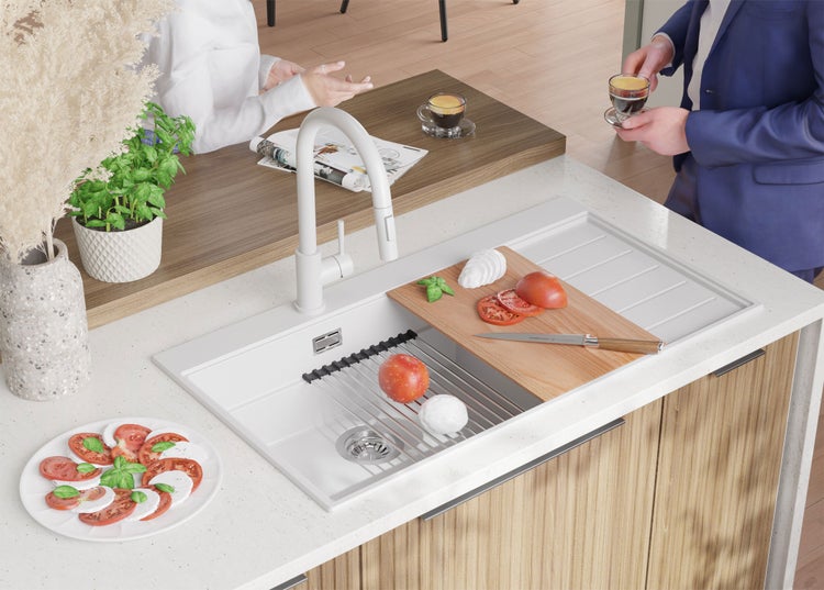 Küchenszene mit Spüle, Armatur, Schneidebrett mit Tomaten und Mozzarella sowie Personen