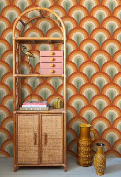 Szene mit einem Regal aus Rattan, Dekoration und einer Wand mit einem Retro-Kreismuster.