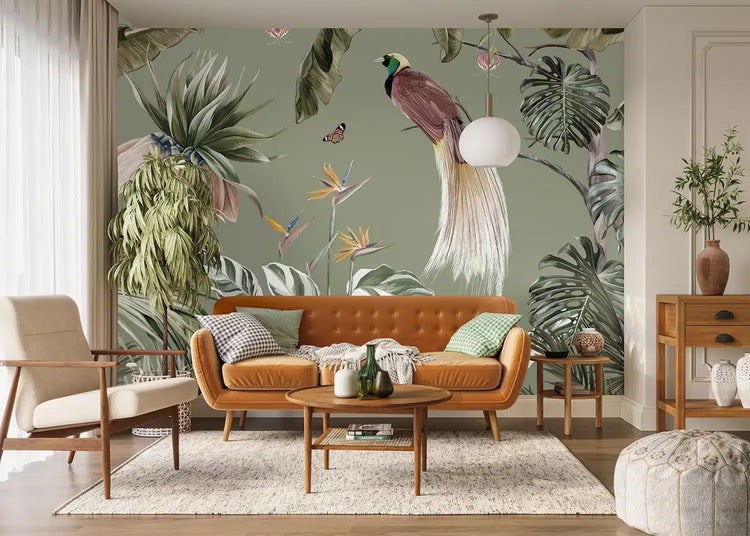 Fototapete mit tropischem Motiv in einem hellen Wohnzimmer. Abgebildet sind ein Paradiesvogel, große Blätter und exotische Blumen hinter einem Sofa.
