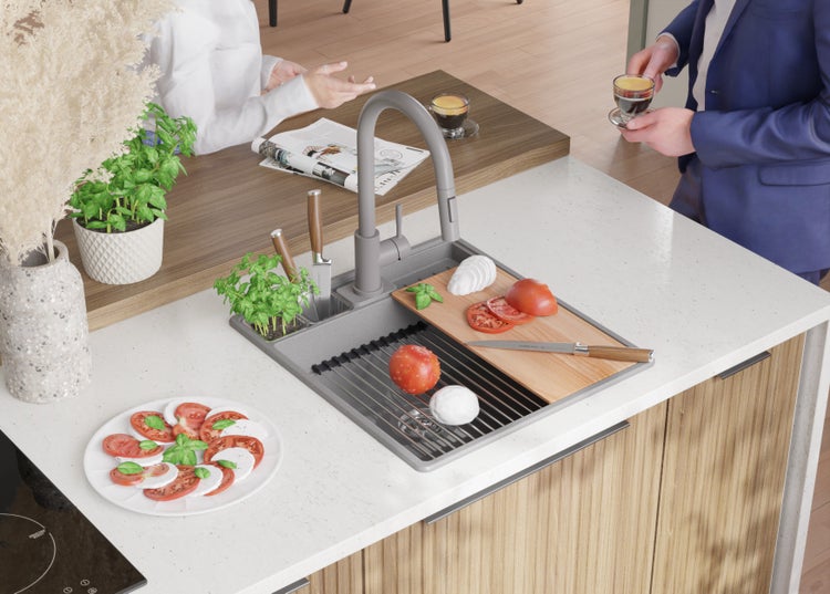 Küchenszene mit Spüle, Armatur, Schneidebrett, Tomaten, Mozzarella, Kräutern und Personen