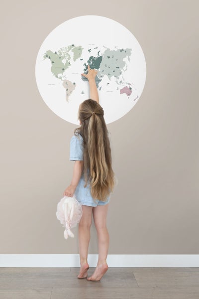 Mädchen zeigt auf eine Weltkarte an der Wand. Wanddekoration für Kinderzimmer.