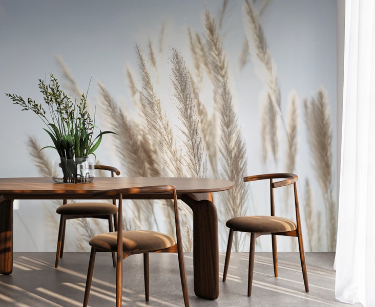 Esstisch mit Stühlen und Blumenvase vor einer Fototapete mit Gräsern