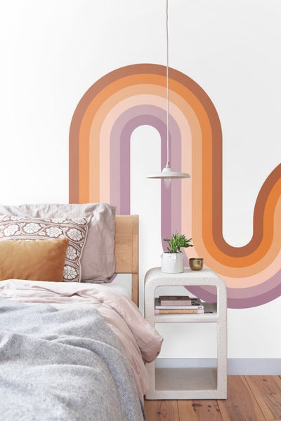 Schlafzimmer mit Bett, Nachttischlampe und mehrfarbigem Wandbild