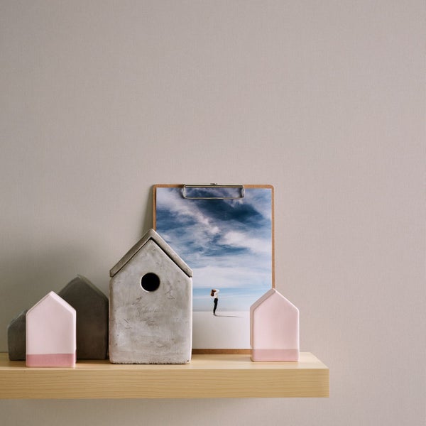 Dekorative Häuser aus Beton und ein Bild auf einem Holzbrett auf einem Regal