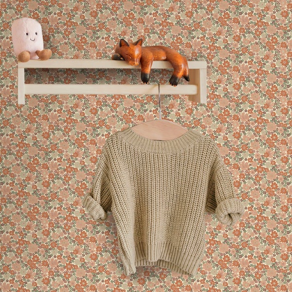 Vliestapete mit kleinteiligem Blumenmuster im Retro-Stil an einer Wand mit Holzregal und hängendem Strickpullover.