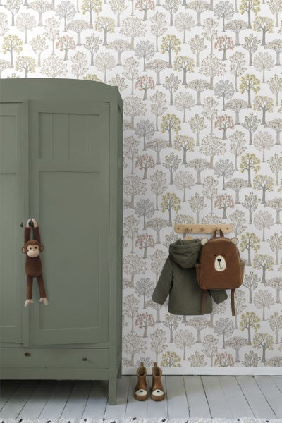 Kinderzimmer mit Tapete im Baumuster, grünem Holzschrank und Wandgarderobe mit Kinderjacke sowie Bärenrucksack.