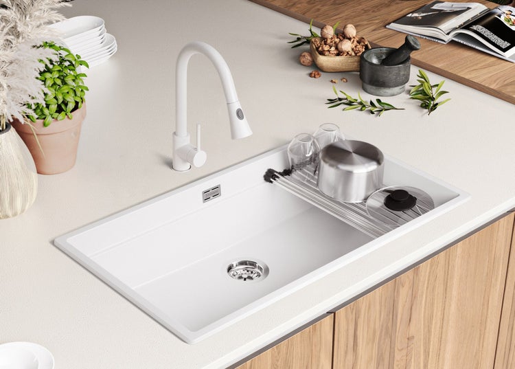 Küchenspüle mit Abtropffläche, Armatur und Geschirr auf einer Küchentheke.