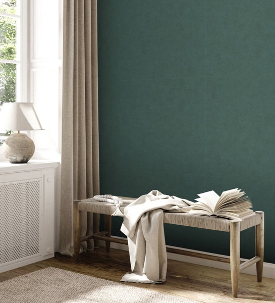 Helle, freundliche Leseecke mit Bank, offenem Buch und Textilien vor einer Wand.