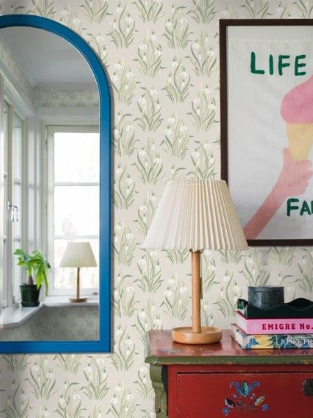 Dekoratives Zimmer mit gemusterter Tapete, Spiegel und Lampe auf einem Tisch