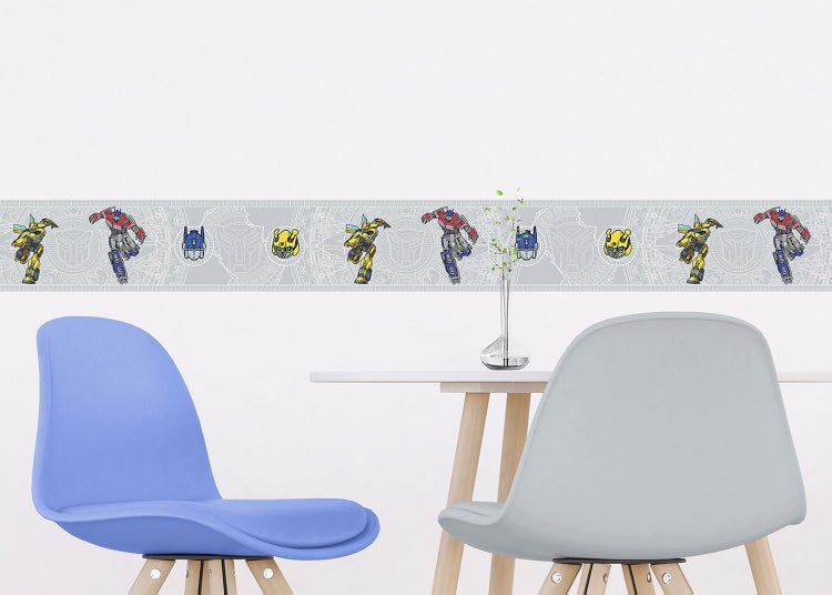Selbstklebende Wandbordüre mit Transformers-Motiven Bumblebee und Optimus Prime in einem hellen Zimmer über einem Tisch mit zwei Stühlen.