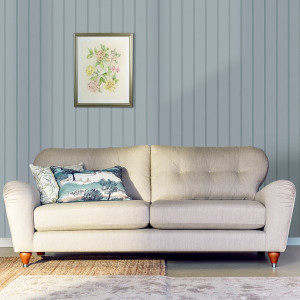 Ein helles Zweisitzer Sofa mit Knopfheftung steht vor einer Wand mit vertikaler Paneeloptik und einem gerahmten Blumenbild an der Wand.