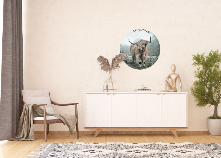 Wohnzimmer mit Sessel, Kommode und Wandtattoo mit schottischem Hochlandrind