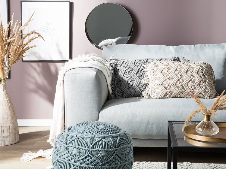 Wohnzimmer mit hellblauem Sofa, Zierkissen, Pouf, Dekoration und Spiegel