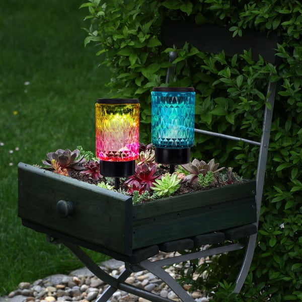 Zwei dekorative Solarleuchten in einem Holzkasten auf einem Stuhl im Garten.