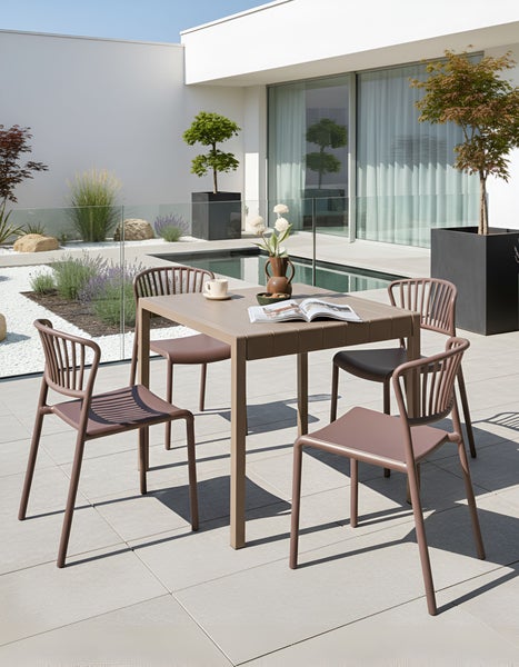 Gartenszene mit Esstisch und vier Stühlen im Außenbereich.