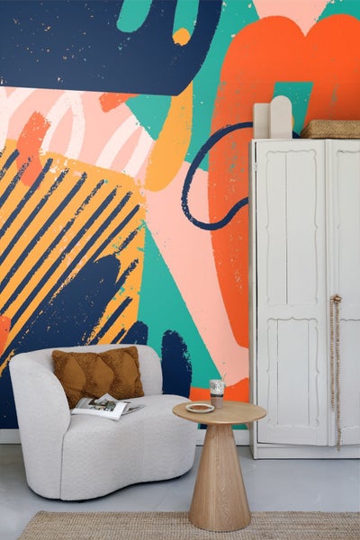 Einrichtungsbeispiel mit abstrakt gemusterter Tapete, Sessel, Beistelltisch und Schrank.