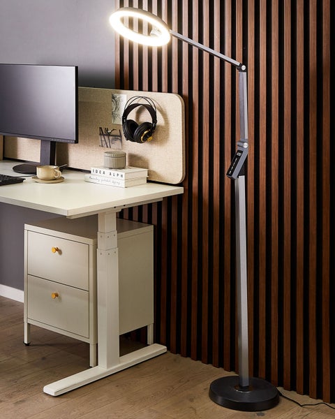 Stehleuchte mit ringförmigem Leuchtmittel neben einem Schreibtisch im Büro