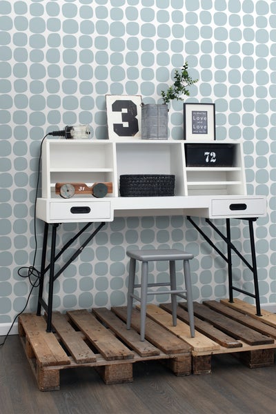 Dekoratives Arbeitszimmer mit Schreibtisch, Stuhl und Holzpaletten als Bodenbelag