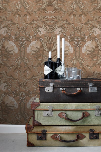 Dekorative Szene mit floraler Tapete, gestapelten Vintage-Koffern, Getränkeflaschen und Kerzen