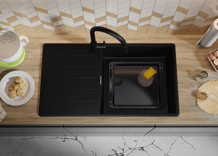 Spüle mit Armatur, Backblech und Spülschwamm auf einer Küchentheke.